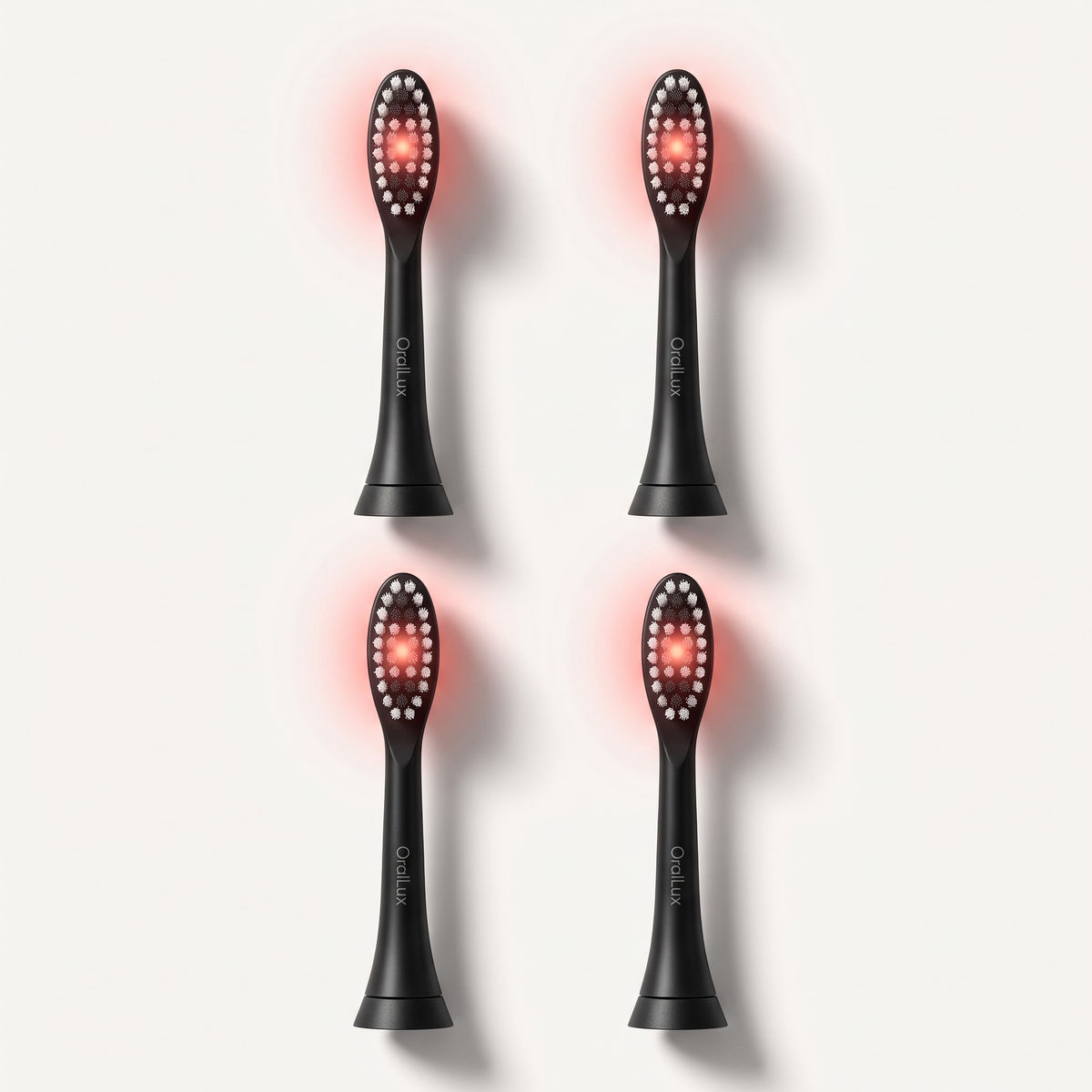 Four matte black OralLux replacement brush heads with red LED bristle fields, arranged in a grid